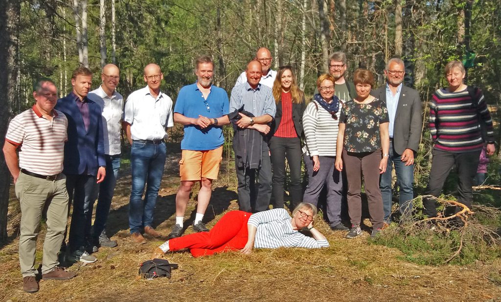 Group of 14 people standing in forest. Photo. 