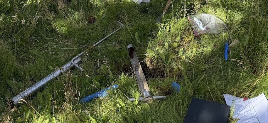 Papers and a few tools laying in grass, sun.