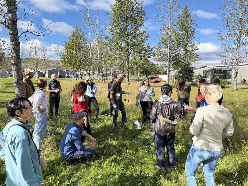 About 10 people in nature, pasture land with a few small trees.