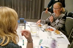 Two woman sitting at table talking. Photo.
