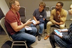 Four people sitting in circle talking. Photo.