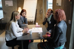 Four people sitting at a black table. Photo.