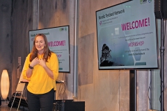 Woman in yellow shirt holding a presentaion. Photo.