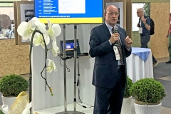 Man holding a microphone, tv screen in the background. Photo.